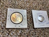 Photo showing both coins in their cardboard holders, the 1967 coin labeled as BU and priced $6.00, and the 1943 coin labeled as King George and Elizabeth II.