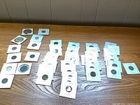 Wide view of vintage and antique coins mounted in cardboard holders spread across a wooden surface, showing large quantity and display style.