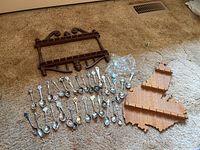 Full lot image showing the two wooden display racks and the spread of spoons on carpeted floor