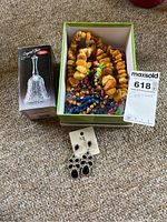 Photo showing crystal bell in box, assorted necklaces including amber bead necklace, colorful bead necklaces, and one pair of black stone drop earrings on card labeled 'ML'