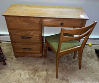 Front view of desk showing four drawers and chair with green padded seat.