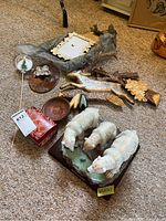 Wider photo displaying a group of carved wood wall art pieces, small wooden bowls, framed art and a glass ornament alongside the Natelia Collection polar bear sculpture.