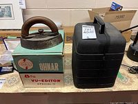 Guelph sad iron, Ohnar VU-Editor box, Bell & Howell projector case on table