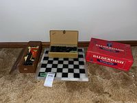 Overall view of Mexican onyx chessboard with chess pieces, wooden boxes with plastic chess pieces and checkers, and Balderdash board game box.