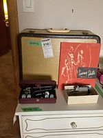 Group shot showing case, sewing machine accessories, templates, buttonholer unit, and reference book