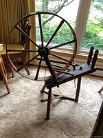 Side angled view of vintage wooden spinning wheel showing wheel and spindles