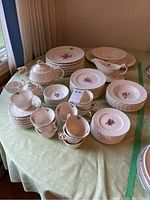 Overview of stacked plates, teacups, saucers, bowls, gravy boat and covered dish on table