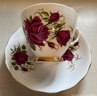 Close-up top view of bone china teacup and matching saucer with pink rose floral pattern and gold trim