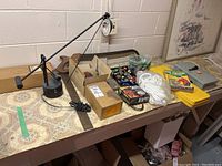 Overview of the lot laid out on a table showing desk lamp, hand bender, switch, electrical parts, hand tools, and accessories.