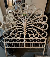 Front view of white wicker peacock style twin bed headboard with curved scroll details and wide fanned feather pattern.