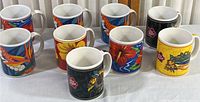 Eight colorful Hawaii-themed ceramic coffee mugs arranged on a surface. Various floral and island scenery designs, no chips or cracks apparent.