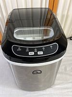 Front top view showing the control panel with LED indicators and buttons, stainless steel finish, and transparent lid window.