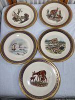Five Lenox Woodland wildlife plates laid out side by side showing different animal scenes and decorative blue and gold borders.