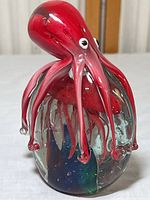 Front-right view showing the red octopus head and tentacles over the clear glass base with internal colored accents.