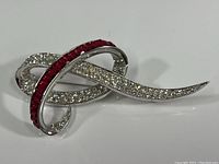 Front view of swirled brooch with clear crystals and ruby red rhinestones on silver-tone metal.