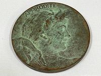 Photo of medallion side with 'Aphrodite' profile with patina and artist signature.