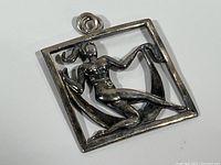 Front view of sterling silver pendant depicting a seated woman holding a flower inside a square frame.