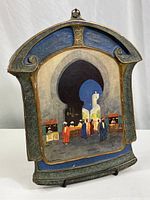 Front view of vintage carved wood plaque with painted Moroccan marketplace scene showing arched corridor and figures in traditional attire.