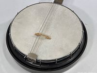 Close-up of the banjo's circular drum-style body with white head and metal brackets.