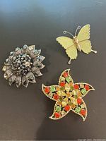 Photo of all three vintage gold tone brooches showing their overall design and condition.