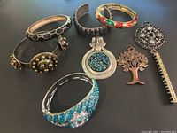 Overview of lot with 7 visible bracelets, pendants and brooches arranged on flat surface