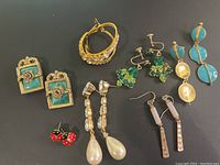 Overall lot view showing nine pairs of assorted vintage earrings of various styles and colors including hoops, drops, studs, and screw-back earrings.