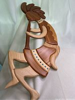 Front view of the handmade wood wall art showing a figure playing a flute in various wood tones with decorative blue dots.
