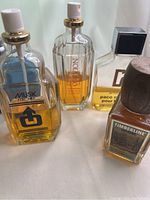 Four vintage men's cologne bottles grouped together showing liquid levels and designs.
