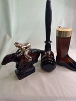 Three vintage Avon aftershave and cologne bottles: cowboy boot, barrel with stopper, and horse with rider.