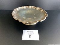 Scalloped edge sterling silver dish viewed from front, showing concave interior and edge detail.