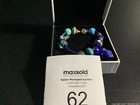 Photo of the bracelet in a black box with the seller's Maxsold auction information