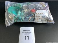 Full view of the sealed bag containing assorted costume jewelry items including necklaces, earrings, and bracelets.