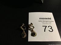 Pair of gold filled screw back earrings with black teardrop stones on a MaxSold auction card