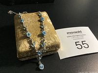 Necklace displayed on a golden-yellow textured jewelry box with a MaxSold auction card.