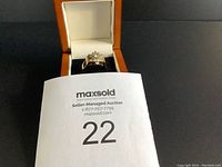 Ring displayed in open ring box with auction lot number card