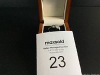 Estate silver-tone ring with two oval clear faceted stones and smaller accent stones on band, inside a jewelry box with auction card in front.