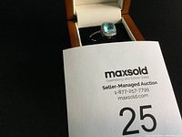 Estate ring with blue topaz center stone in a jewelry box, accompanied by auction information card.