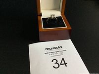 Silver ring displayed in a wooden and white jewelry box with MaxSold auction lot number in the foreground.