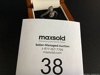 Silver snake design ring in jewelry box with auction lot number card partially visible.