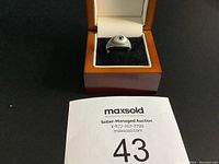 Estate eye motif ring in wooden jewelry box from front view.