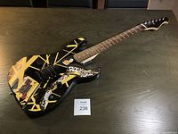 Full view of Spectrum electric guitar with yellow stripe design and multiple stickers including 'Rock and Roll'.