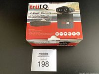 Box front showing truIQ HD Dash Camera, highlighting 2.4" TFT LCD screen, HD DVR, still camera mode, video recording, support for up to 32GB memory card. The device pictured on box has a compact screen and lens array.