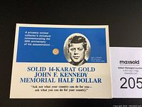 Photo of the commemorative display card with JFK portrait and the 14-karat gold coin embedded on the card's front.