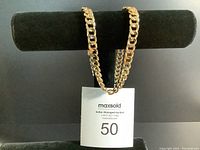 Gold-tone chain necklace displayed on a black velvet holder showing the chain links and gold color.
