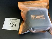 Sealed orange resealable bag with Slonik logo containing the headlamp and accessories.