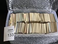 Plastic tote filled with stacks of trading cards viewed from above showing quantity and storage condition.