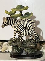 Photo of zebra figurine showing two zebras standing on a textured base with leafy accents.