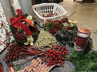 Various Christmas decorative picks, bows, and floral accents including red berry picks, cream berries, poinsettias, pinecones, and boxed silk flowers.