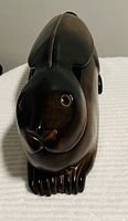 Top front view of dark brown polished stone rabbit figurine with detailed face and paws.