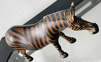 Side view of the wooden zebra figurine showing detailed painted stripes and overall shape